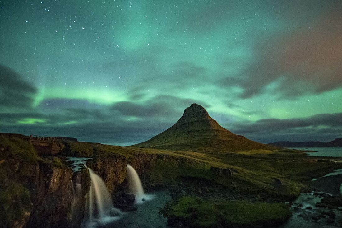 Aurora boreal sobre el monte Kirkjufell y su cascada, Islandia