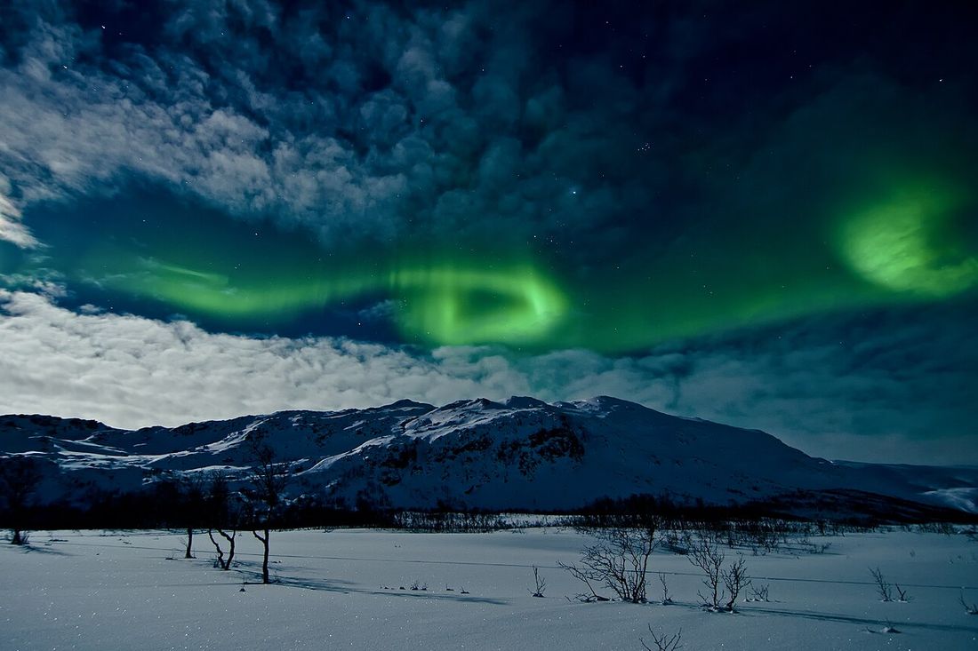 Aurora boreal sobre las montañas nevadas de Tromsø, Noruega