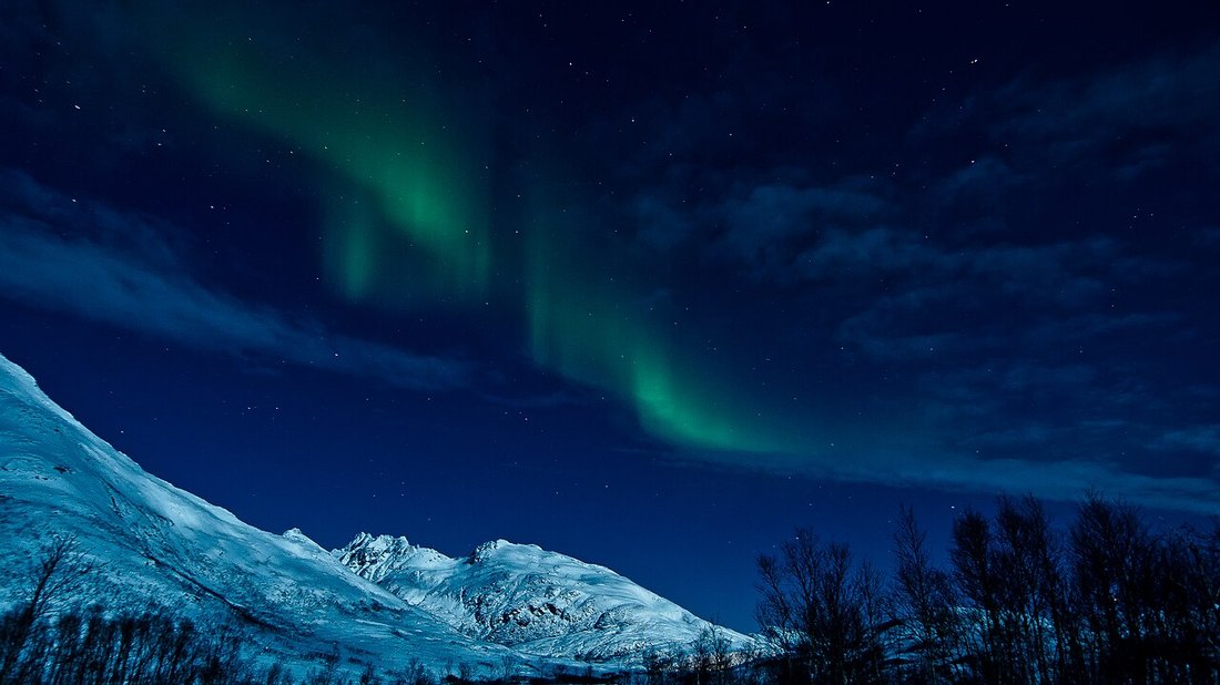 Aurora boreal verde sobre un paisaje nevado del Ártico